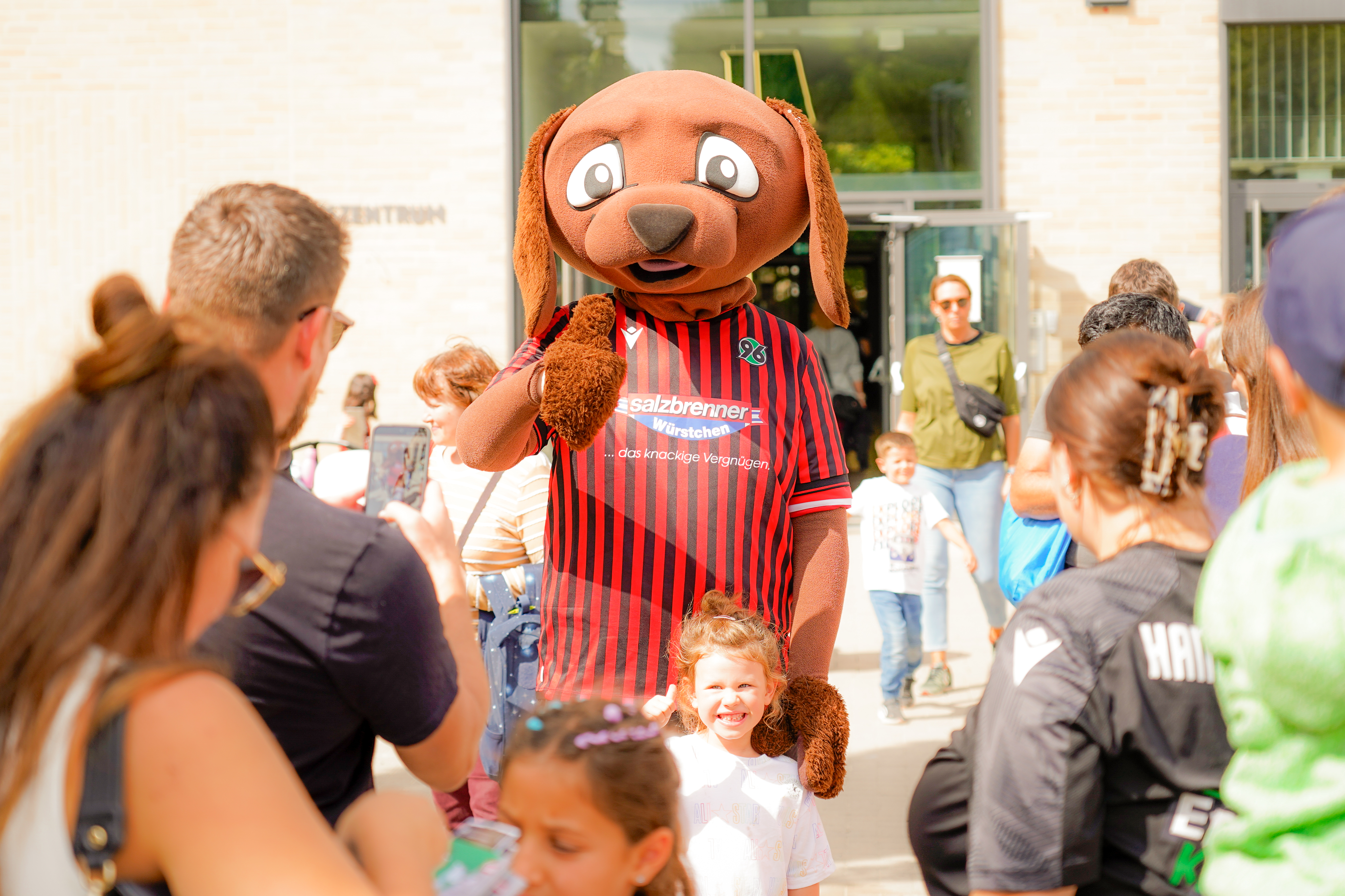 Maskottchen EDDI in der Menschenmenge mit dem Daumen hoch.
