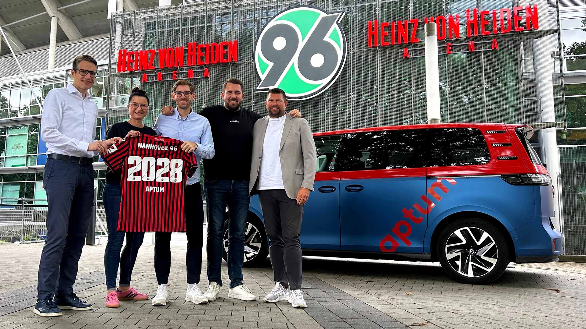 Verantwortliche von Hannover 96 und aptum präsentieren ein 96-Heimtrikot mit dem Flock "2028 APTUM".