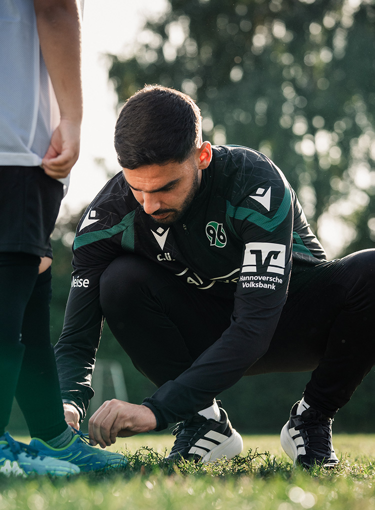 Can Ünal macht einem Kind die Schuhe zu.