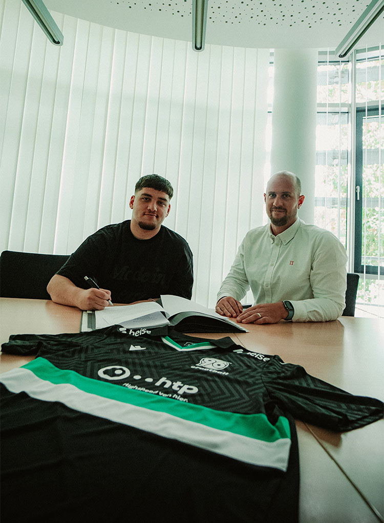 Musti bei der Unterschrift mit 96-eFootball-Leiter Paul Wetenkamp, im Vordergrund liegt das neue eFootball-Trikot.
