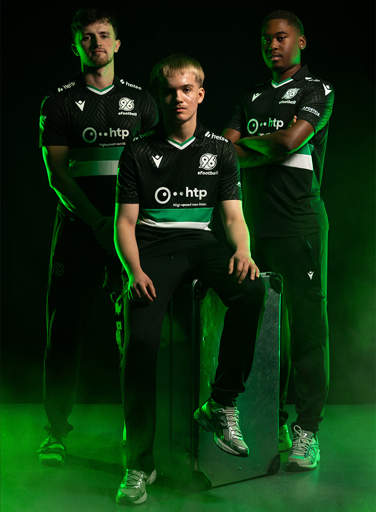Die drei eFootball-Spieler vor schwarzem Hintergrund, einer sitzt auf einer silbernen Kiste, zwei stehen.