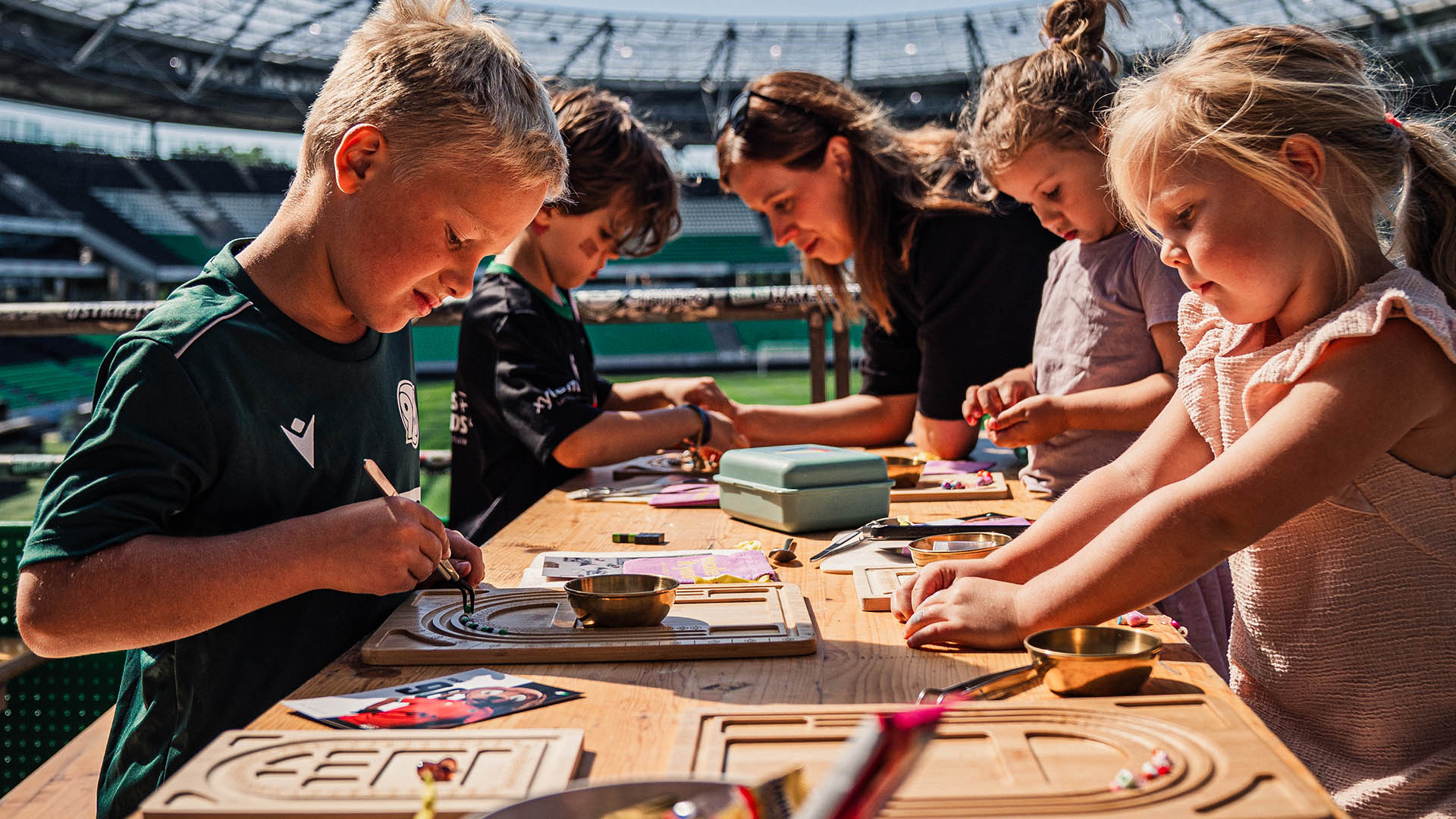 Viele Kids basteln Freundschaftsbänder mit Blick ins Stadion.