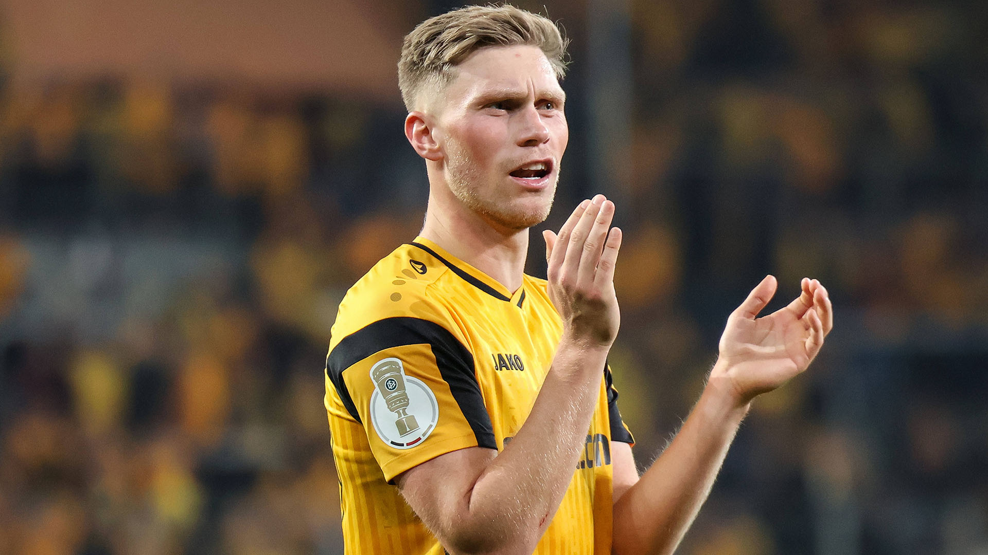 Jonas Sterner klatscht im gelben Dresden-Trikot in die Hände.