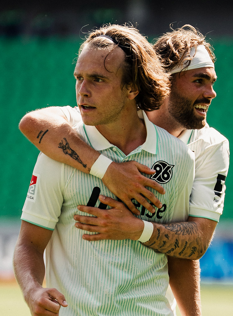 Kolja Oudenne umarmt Lars Gindorf von hinten. 
