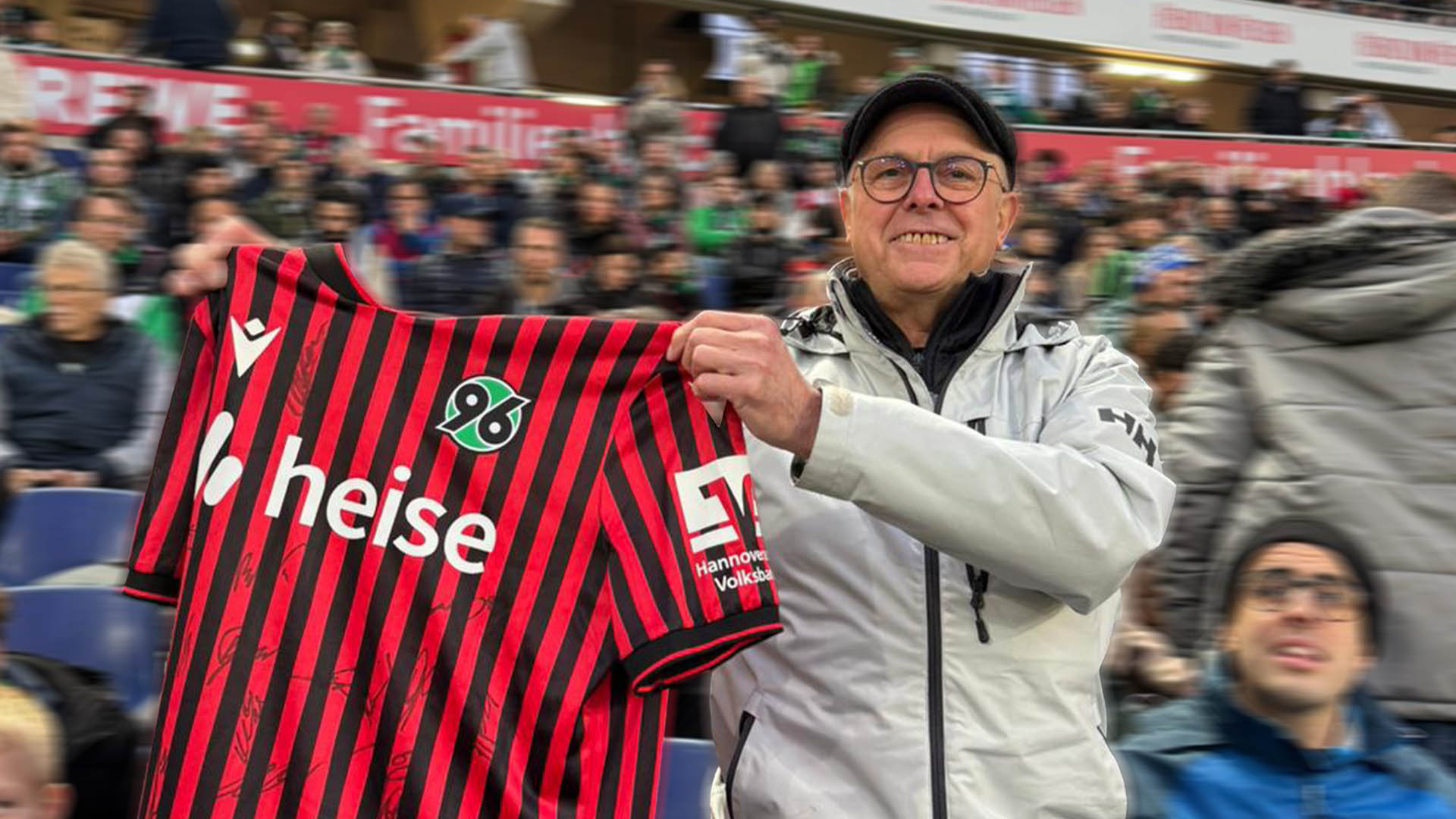 Ein Mann hält ein signiertes 96-Trikot in die Kamera.