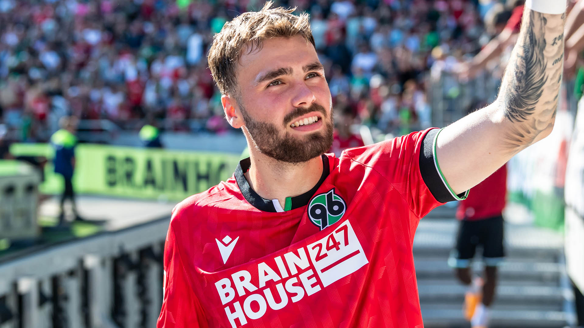 Kolja Oudenne klatscht im roten Trikot mit Fans ab.