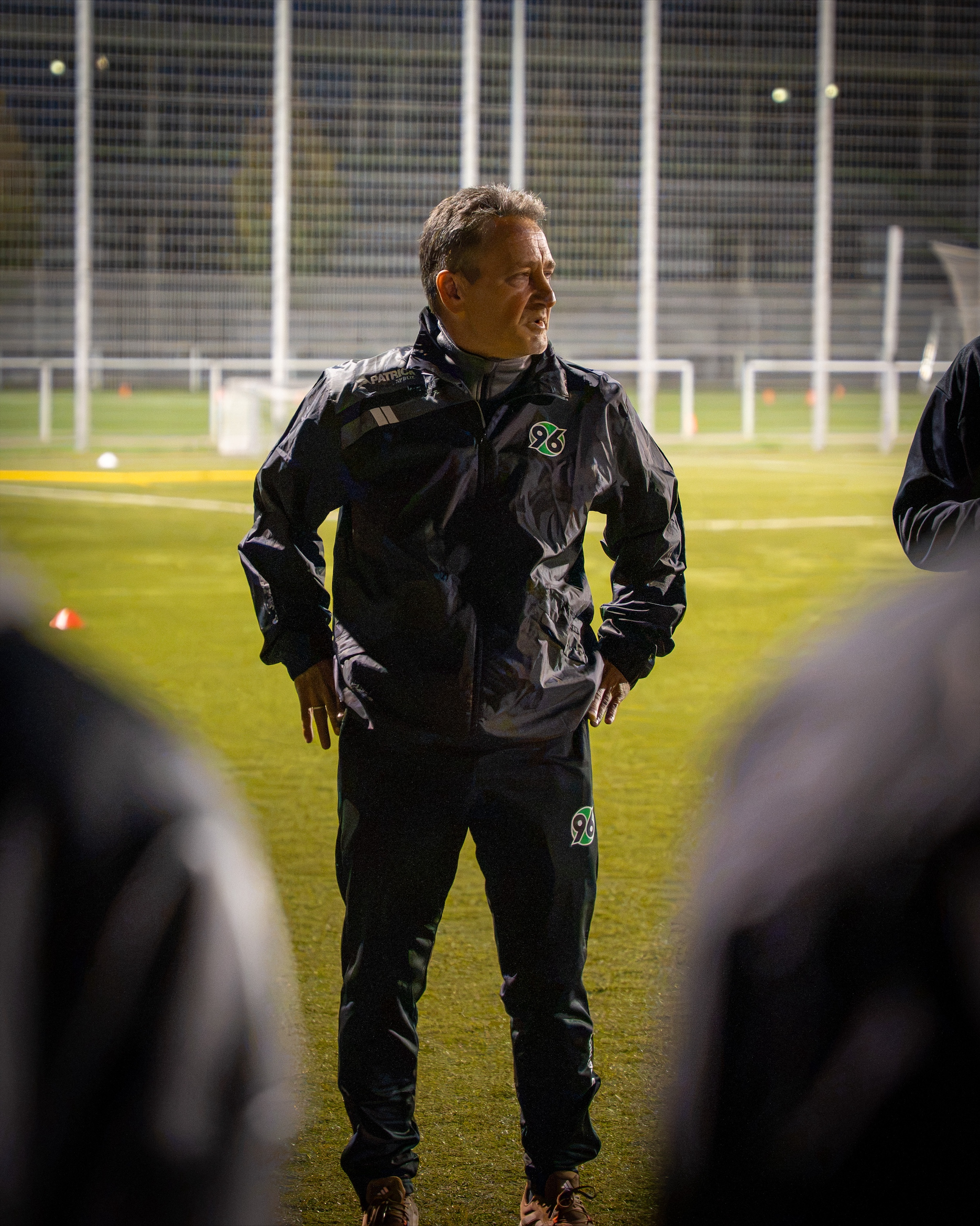 Der Trainer steht vor seinen Spielerinnen auf dem Spielfeld.