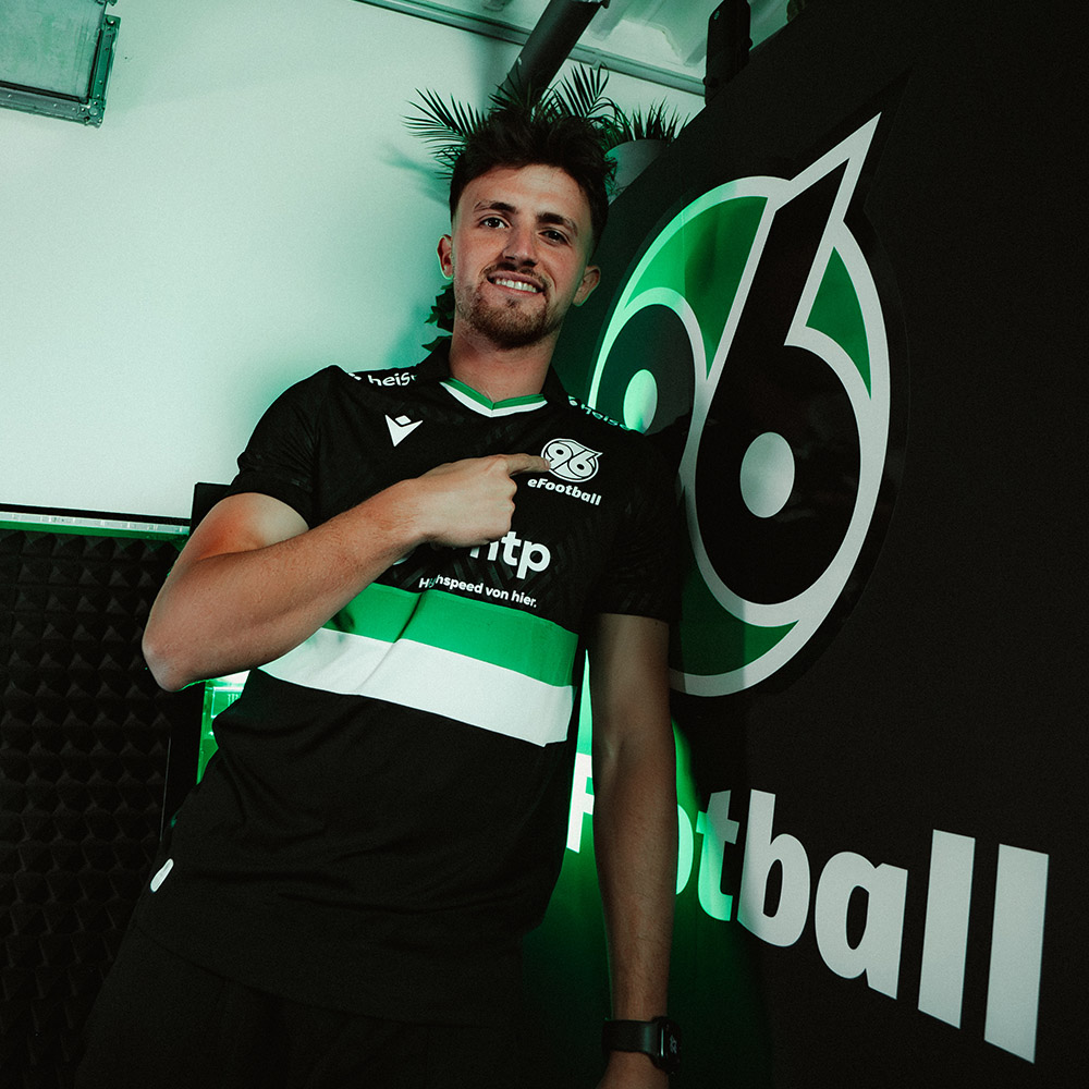 Riad zeigt mit dem Finger auf 96-Logo.