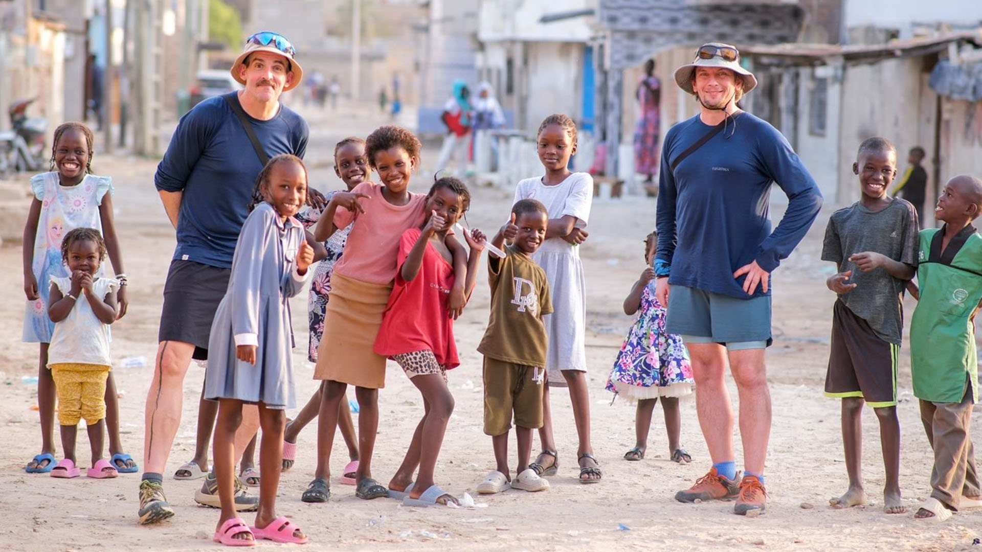 Anthony Horyna und Dominik Singer stehen in einem Dorf im Senegal.