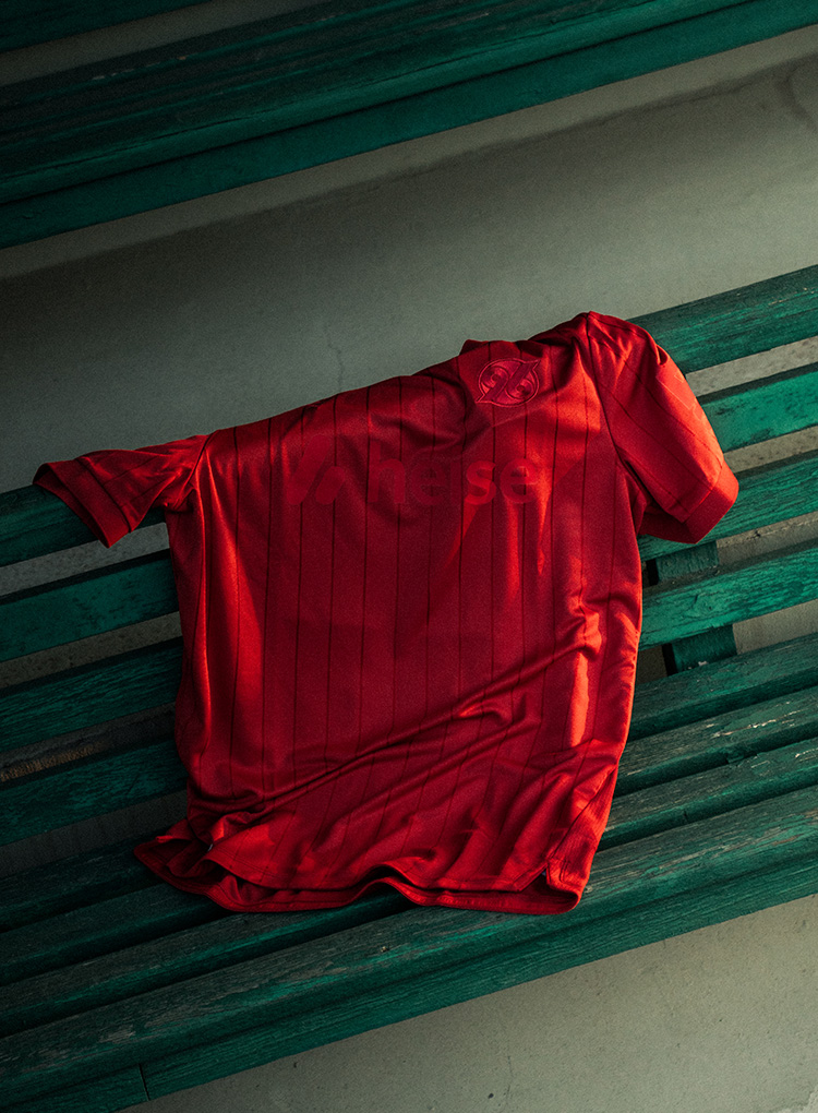 Ein rotes 96-Trikot liegt auf einer Sitzbank.