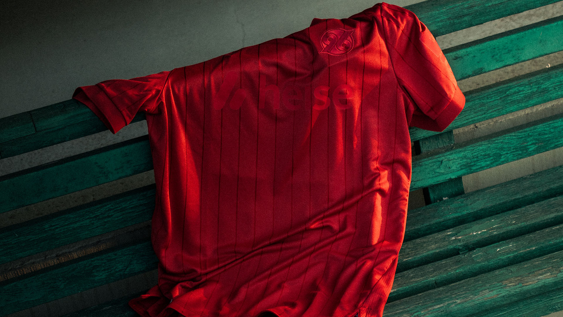 Ein rotes 96-Trikot liegt auf einer Sitzbank.