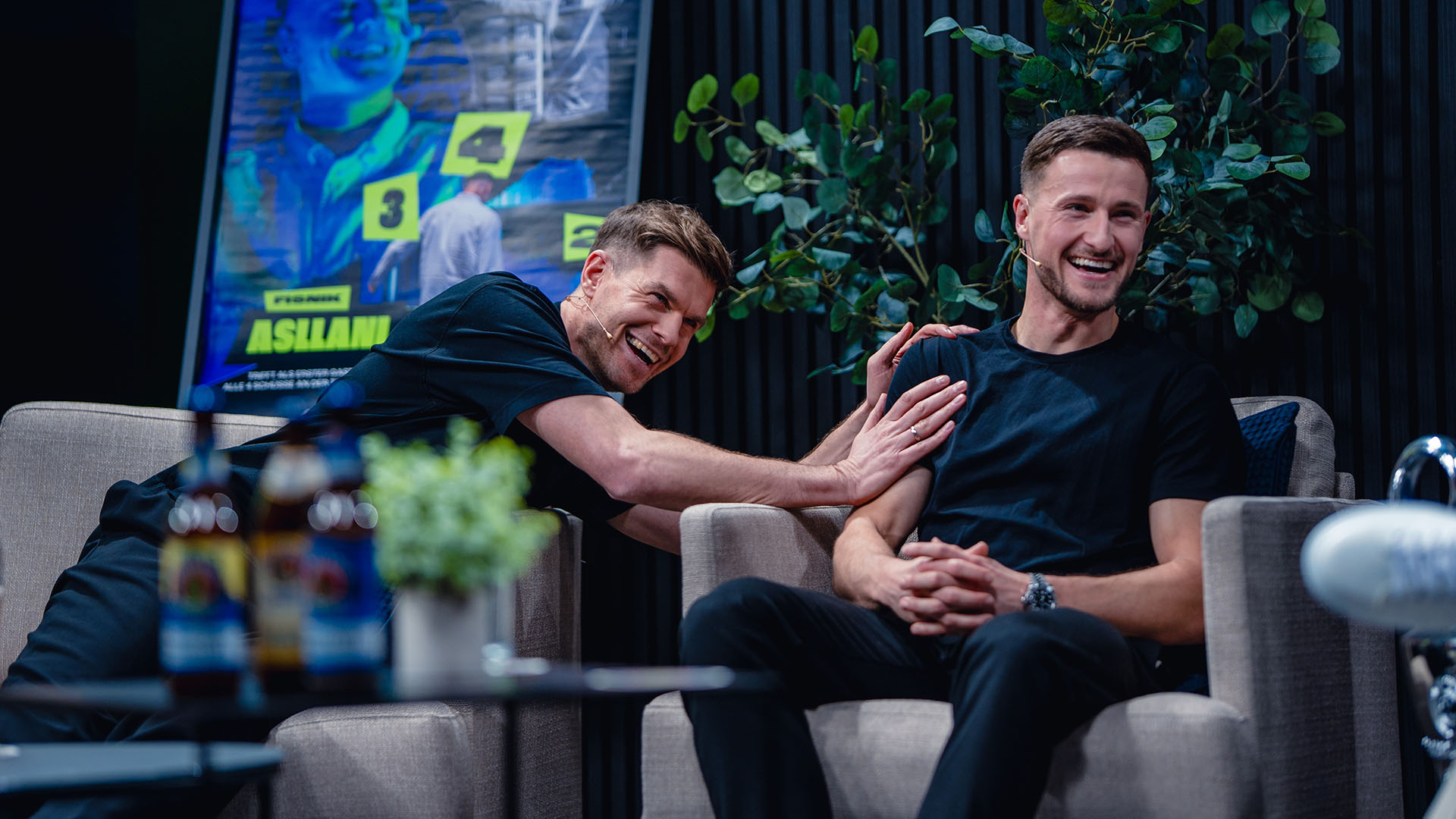 Simon Terrode (links) und Leopold lachen in einem Talkshow-Setting.