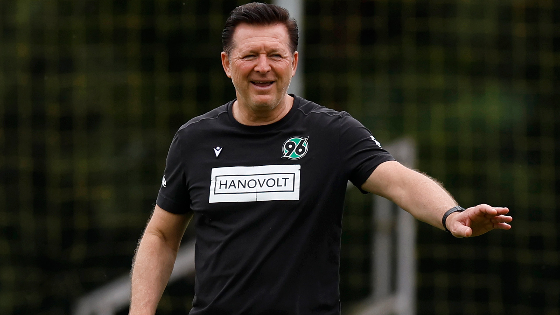 Christian Titz gestikuliert lächelnd auf dem Trainingsplatz.