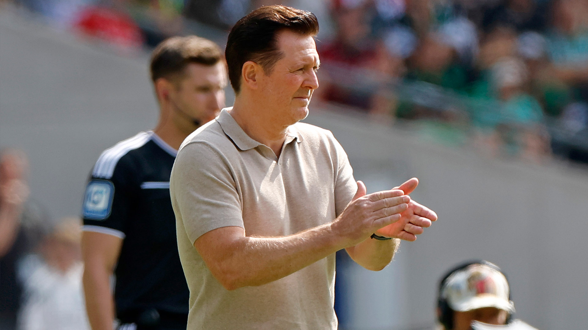 Christian Titz steht klatschend am Spielfeldrand.